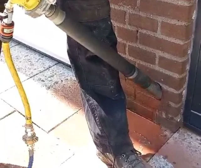 Ventilatieboring onderaan een gemetselde gevel