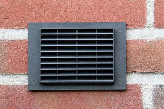 Zwart ventilatierooster in een gemetselde buitenmuur