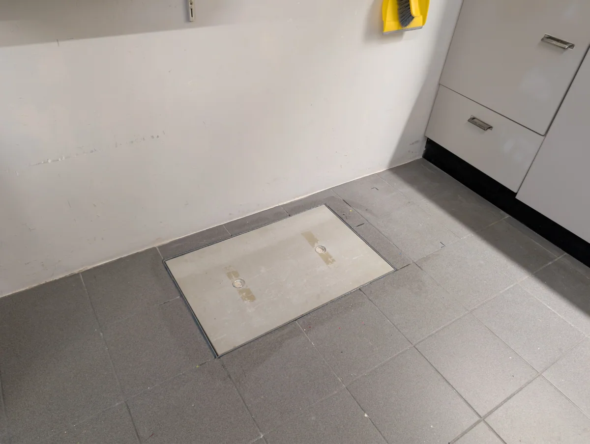 Geplaatst kruipluik met metalen omranding in een bestaande tegelvloer