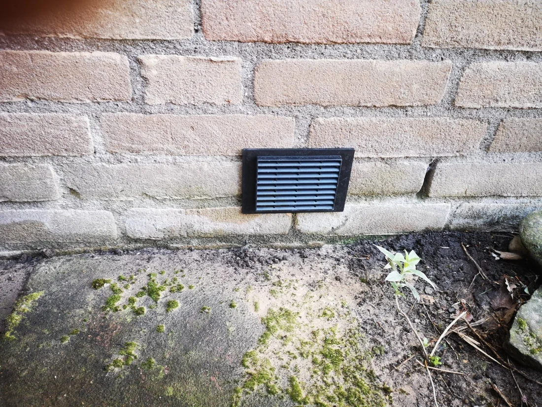 Een afgewerkt ventilatiepunt laag in de buitengevel.